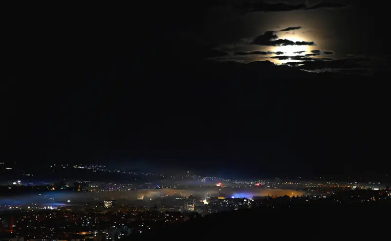 Felhős éjszaka - fény a város fölött